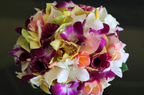Tropical bouquet with white dendrobium orchids, purple dendrobium orchids, green cymbidium orchids, plumeria, and white anthurium. 